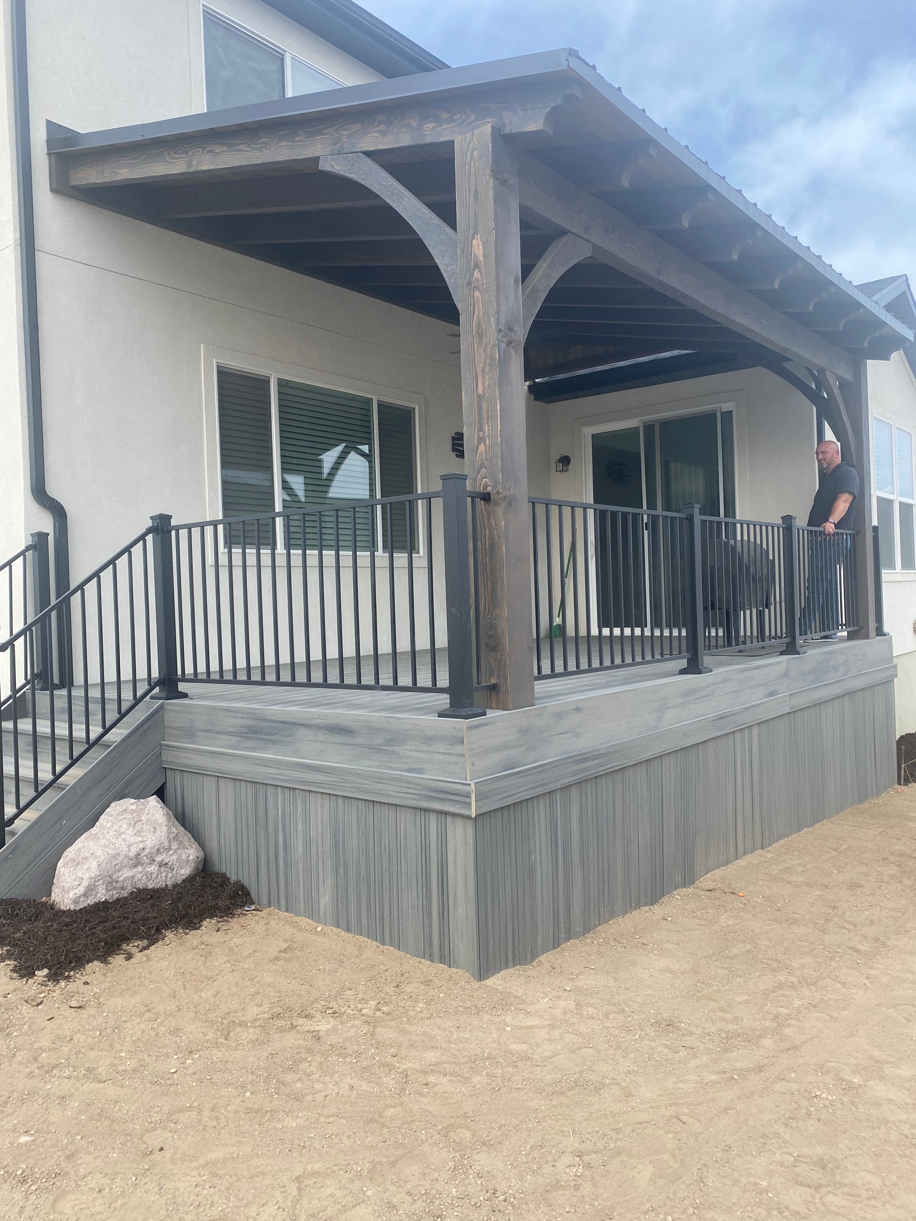 gray composite custom deck builder with custom wood covered metal roof and black powder coated handrail